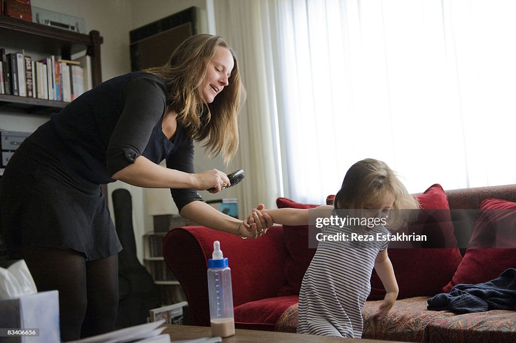 Mother tries to brush playful daughter's hair