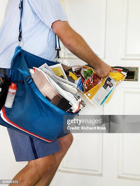 a mailman stuffing junk mail into a mailbox - postal worker stock pictures, royalty-free photos & images