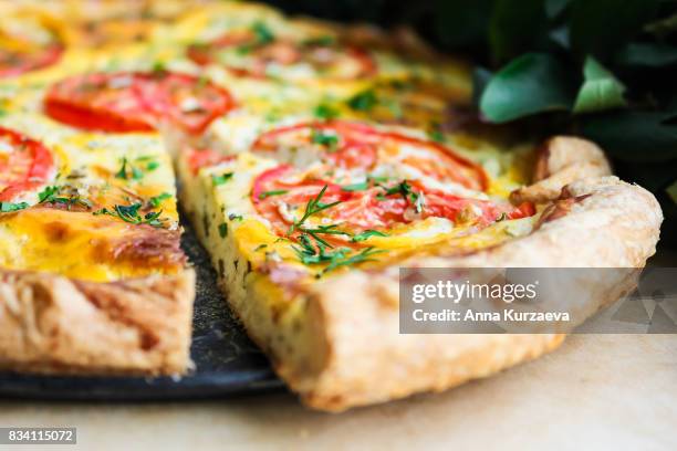 slice of homemade tomato pie, pizza or quiche with curd cheese, eggs and fresh chopped parsley on a wooden plate perfect for summer picnic or snack, selective focus - savory pie stockfoto's en -beelden