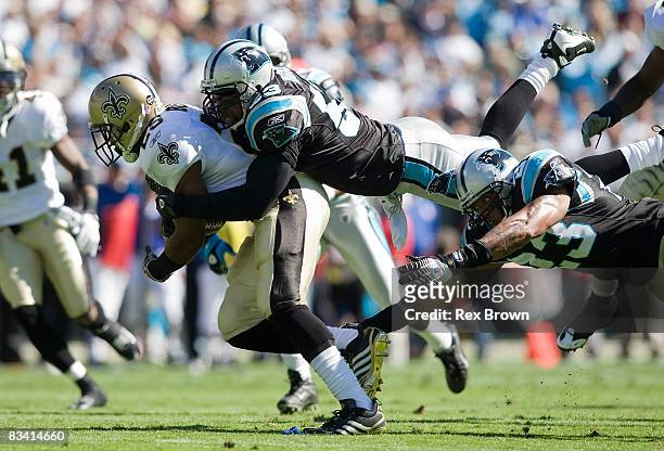Dante Wesley and Na'il Diggs of the Carolina Panthers tackles Reggie Bush of the New Orleans Saints during the first half at Bank of America Stadium...