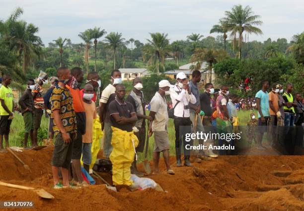 Men wait beside empty graves for the coffins of mudslide victims on August 17, 2017 at Waterloo cemetery near Freetown, Sierra Leone. 600 people are...