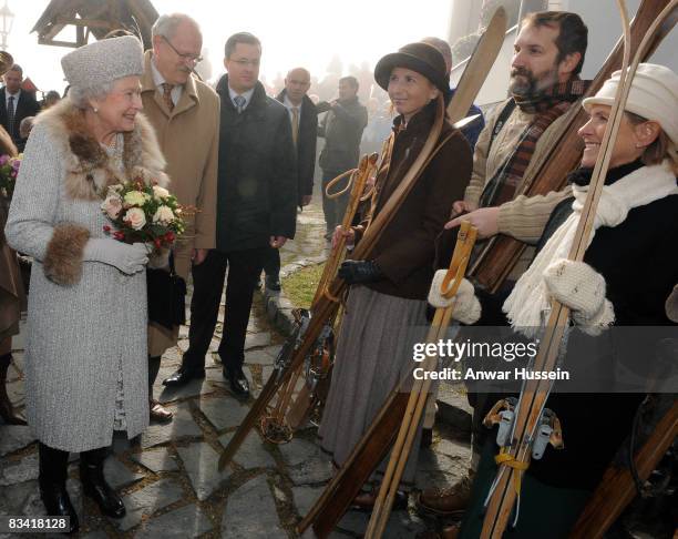 Queen Elizabeth II looks at locals holding antique skis as she tours Hrebienok Ski Resort on the second day of a tour of Slovakia on October 24, 2008...