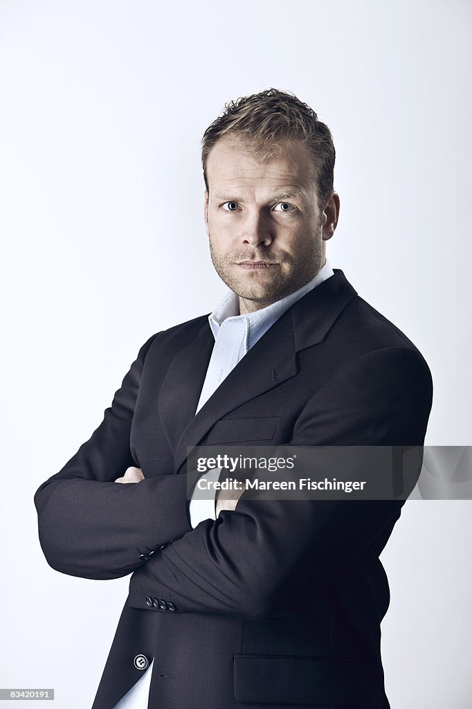 Man standing with arms crossed, studio portrait