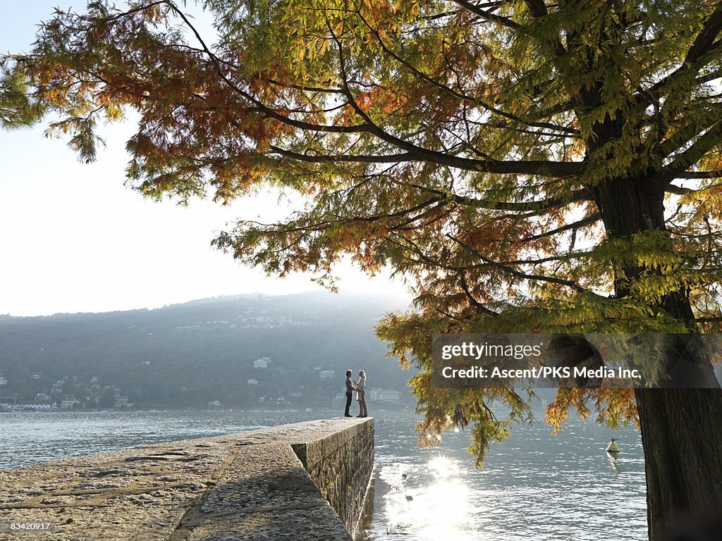 Man and woman stand at end of stone pier