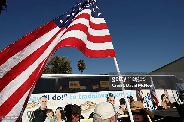 Man carries a flag as supporters of Proposition 8, which would outlaw same-sex marriage throughout California, rally during a 'Yes on 8 bus tour'...