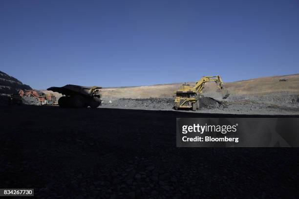Dump truck, left, waits to move into position as an excavator deposits ore into another dump truck at the White Foil open pit mine at Evolution...