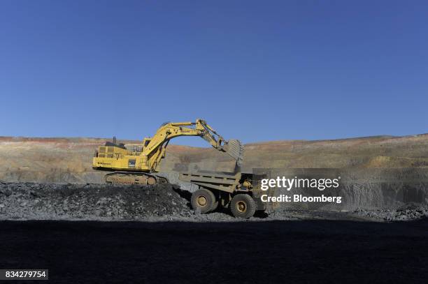 An excavator deposits ore into a dump truck in the White Foil open mine pit at Evolution Mining Ltd.'s gold operations in Mungari, Australia, on...