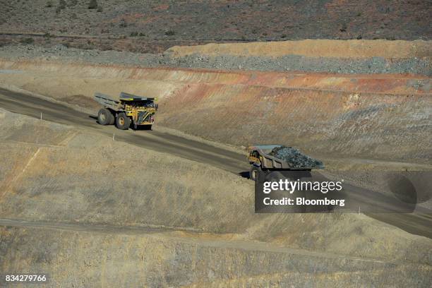 Dump trucks drive along an access ramp in the White Foil open mine pit at Evolution Mining Ltd.'s gold operations in Mungari, Australia, on Tuesday,...