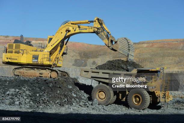An excavator deposits ore into the back of a dump truck in the White Foil open mine pit at Evolution Mining Ltd.'s gold operations in Mungari,...