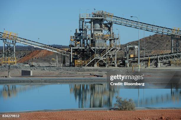 Water reserve pond sits in front of conveyors at the processing plant of Evolution Mining Ltd.'s gold operations in Mungari, Australia, on Tuesday,...