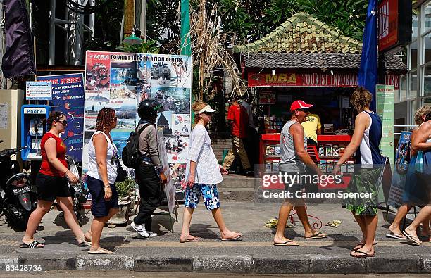 Tourists walk past a tourist operator at Kuta Beach on October 25, 2008 in Bali, Indonesia. Tourism continues in Bali despite the Australian...