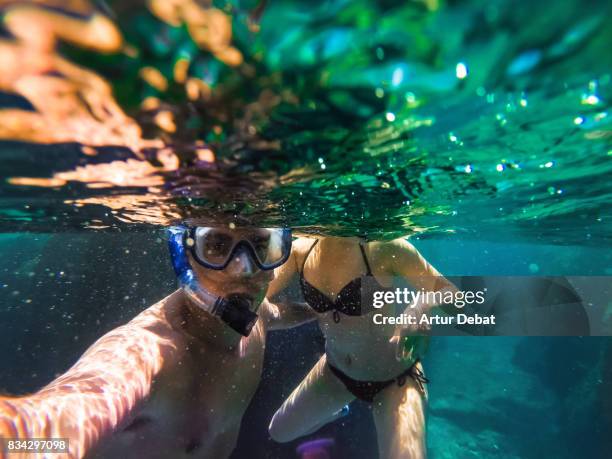 couple doing snorkel taking a selfie exploring the natural cave in the shoreline of costa brava mediterranean sea during summer vacations in a paradise place taking picture with dome cover and underwater view. - calella de palafrugell photos et images de collection