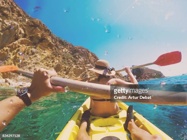 Couple doing kayak taking picture from boyfriend personal perspective exploring the natural Medes islands in the shoreline of Costa Brava Mediterranean Sea during summer vacations in a paradise place.