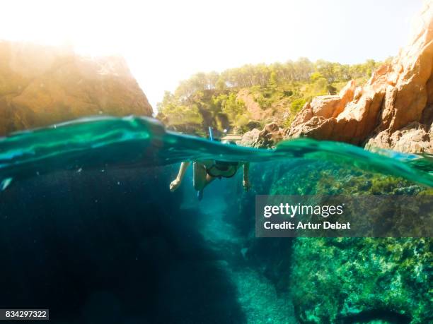 girl doing snorkel exploring the natural cave in the shoreline of costa brava mediterranean sea during summer vacations in a paradise place taking picture with dome cover and underwater view. - calella de palafrugell photos et images de collection