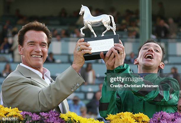 Governor Arnold Schwarzenegger and jockey Frankie Dettori, riding Raven?s Pass ,, pose with the Breeder's Cup Classic trophy during the Breeders' Cup...