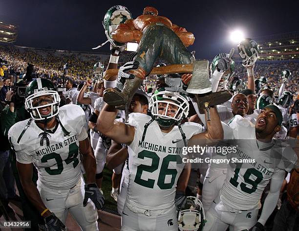 Jesse Johnson of the Michigan State Spartans holds up the Paul Bunyan trophy between David Williams and Brandon Denson after beating the Michigan...