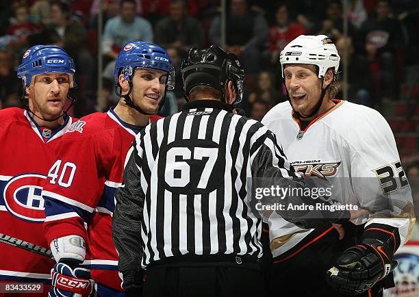 Maxim Lapierre of the Montreal Canadiens and Travis Moen of the Anaheim Ducks laugh as they are separated from a scrum by linesman Pierre Champoux as...