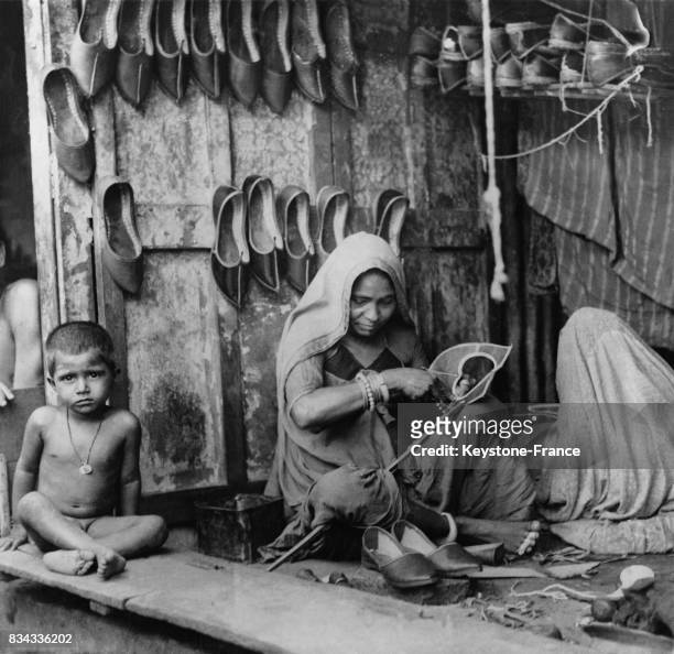 Une femme fabrique des chaussures en cuir dans une échoppe en Inde.