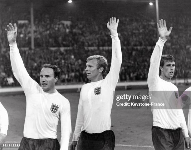 Le capitaine Bobby Moore , George Cohen et Geoff Hurst saluent la foule après la victoire de l'Angleterre en demi-finale, au stade de Wembley,...