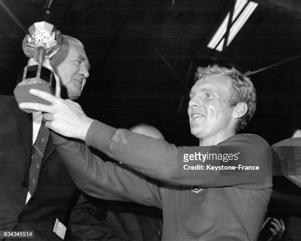 Le capitaine anglais Bobby Moore soulève avec fierté le trophée que l'équipe d'Angleterre a gagné, à Londres, Royaume-Uni le 30 juillet 1966.