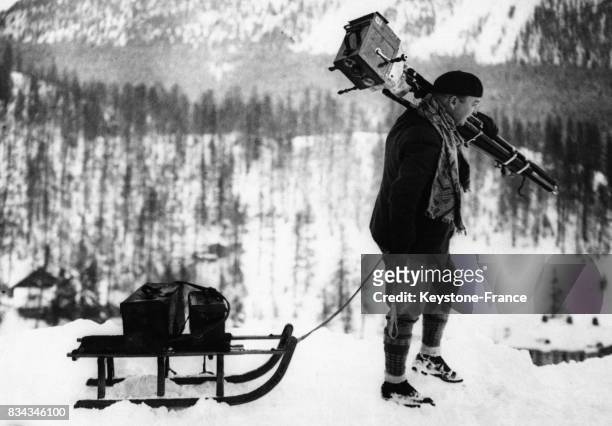 Un opérateur de cinéma tire un traineau portant son matériel dans les montagnes en Suisse.