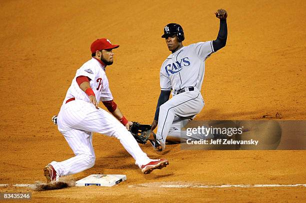 Pedro Feliz of the Philadelphia Phillies cannot scoop a low throw and BJ Upton of the Tampa Bay Rays is safe at third and then scores on the throwing...