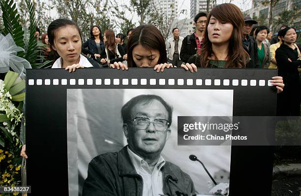 People hold the portrait of the famed Chinese film director Xie Jin attending Xie's funeral at the Longhua Funeral Home on October 26, 2008 in...