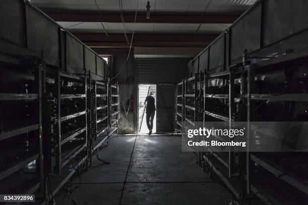 Technician exits a warehouse containing bitcoin mining machines at a mining facility operated by Bitmain Technologies Ltd. In Ordos, Inner Mongolia,...