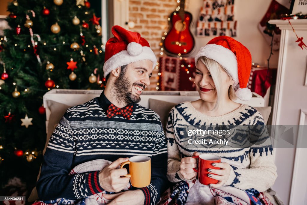 Par avkoppling och dricka te framför en julgran