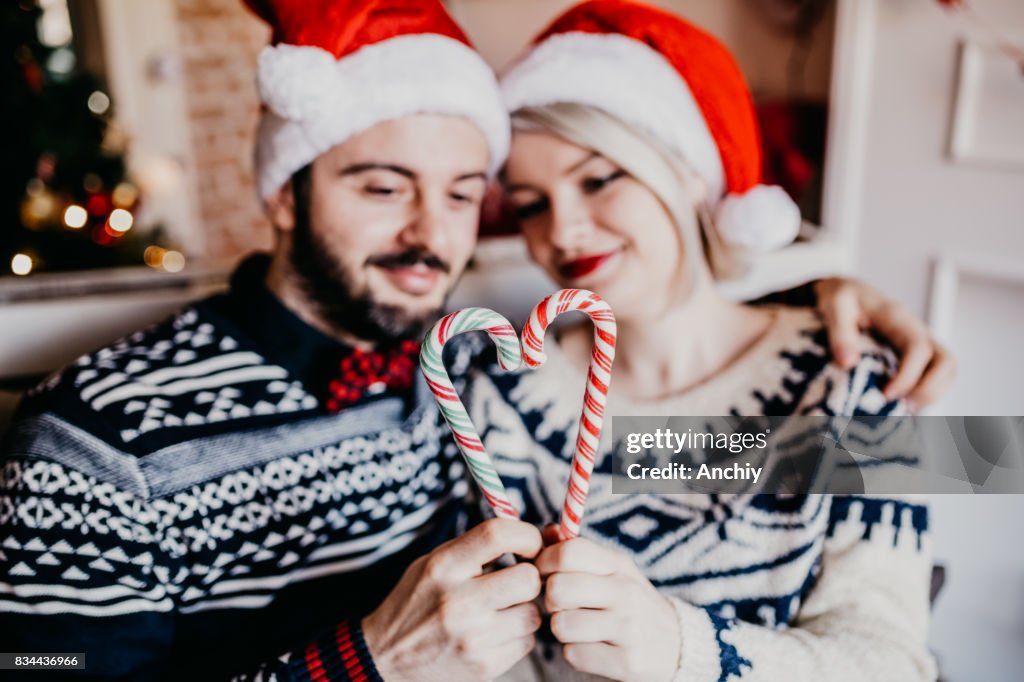Beautiful couple making heart shape from Christmas candy cane