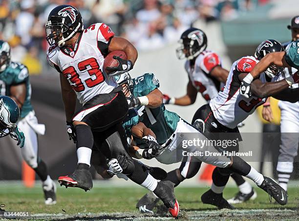 Running back Michael Turner of the Atlanta Falcons runs with the ball while getting pulled down by linebacker Chris Gocong of the Philadelphia Eagles...