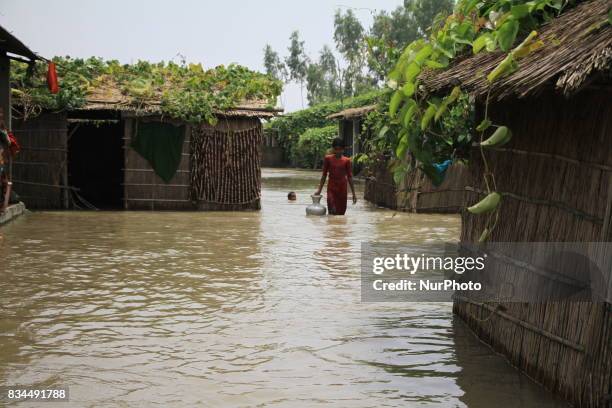 Bangladeshi girl walks in flood water to collect drinking water from a tube well at a shelter center in Gaibandha, northern Bangladesh on August 15,...