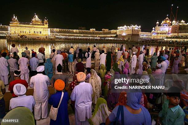 Indian Sikh devotees offer prayers in front of the illuminated Golden Temple on the eve of the festival of Bandi Chhor Divas in Amritsar on October...