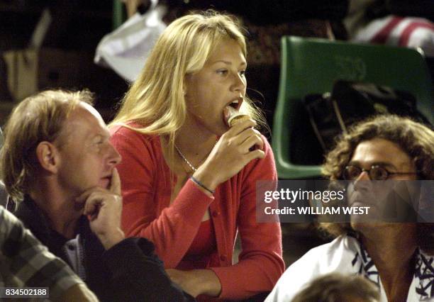 Anna Kournikova of Russia licks ice-cream from a cone while sitting in the players' seating area watching the men's quarter-final match between...