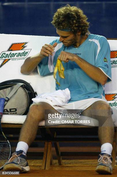 Brazilian tennis player finishes a snack during his match against Spain's David Ferrer 26 February 2003. El brasileno Gustavo Kuerten termina de...
