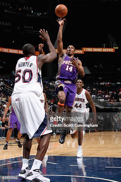 Sean Singletary of the Phoenix Suns goes up for a shot over Othello Hunter and Solomon Jones of the Atlanta Hawks during the preseason game on...