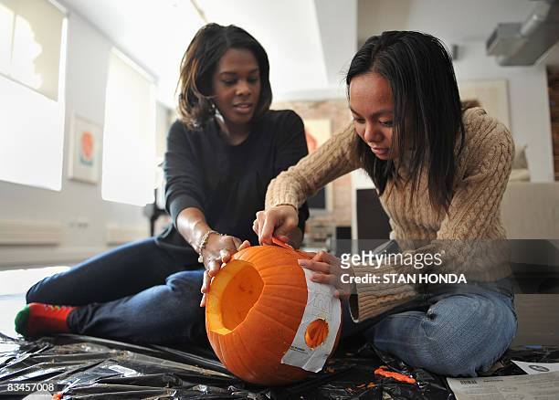 Jazel Cuyan and Tomiko Cary carve a Halloween pumpkin using a stencil with the name of Democratic presidential candidate Illinois Senator Barack...