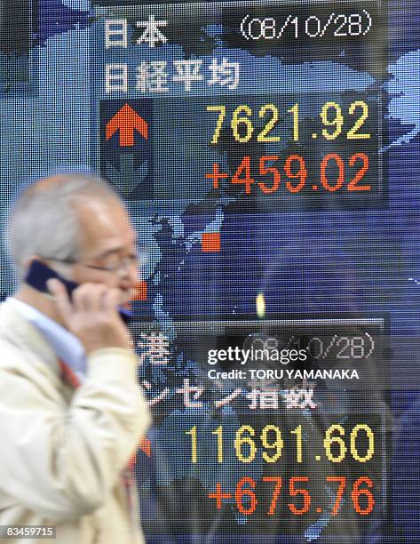 Pedestrian walks past an electronic quotation board flashing the Nikkei key index of the Tokyo Stock Exchange in front of a securities company in...