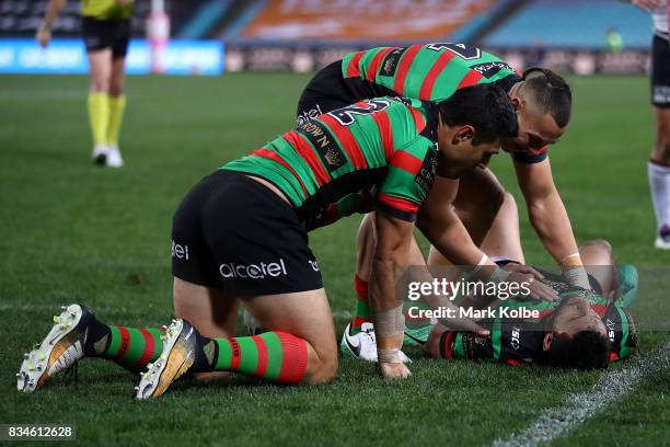 Tyrell Fuimaono and Bryson Goodwin of the Rabbitohs congratulate Alex Johnston of the Rabbitohs as he lies injured on the ground after scoring a try...