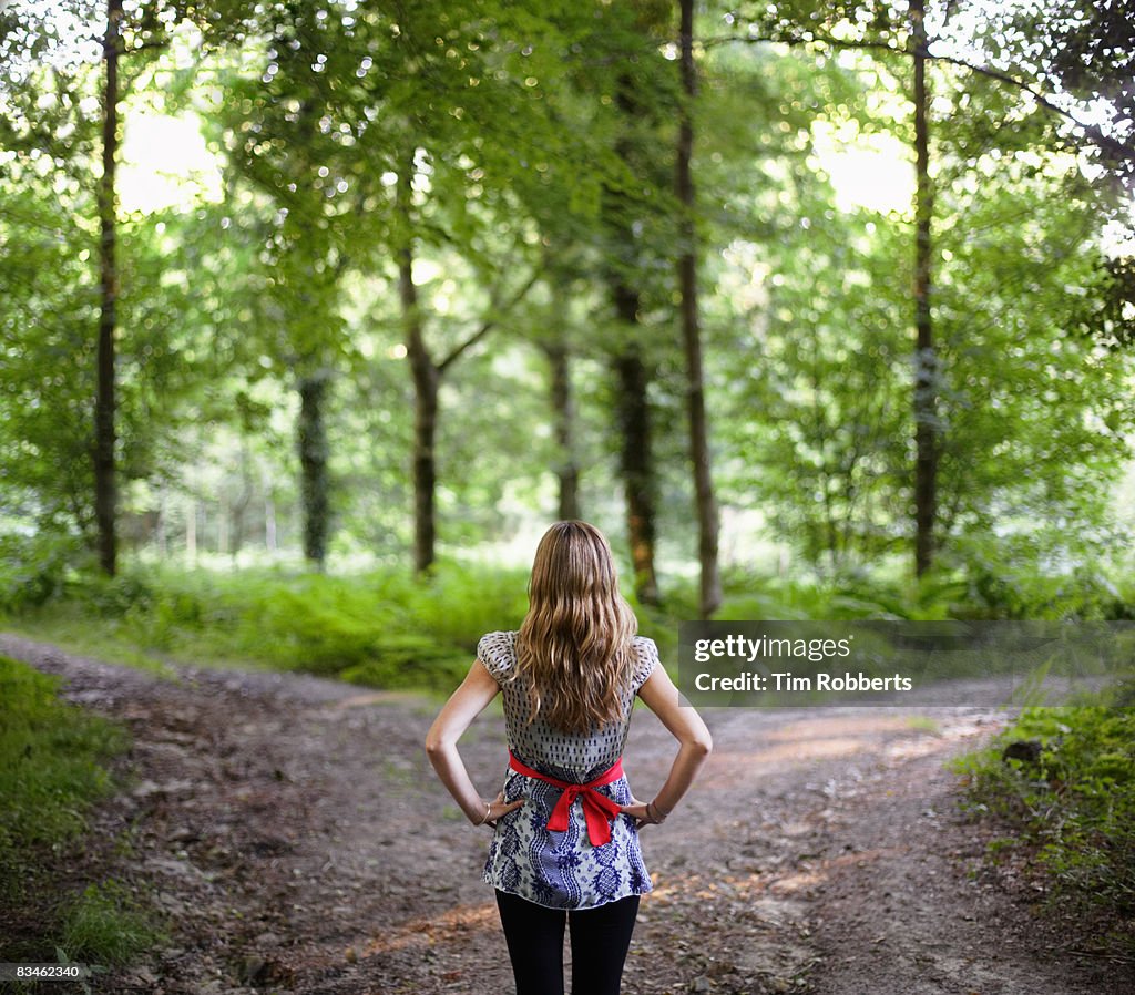 Young woman using laptop sat on tree trunk in fore