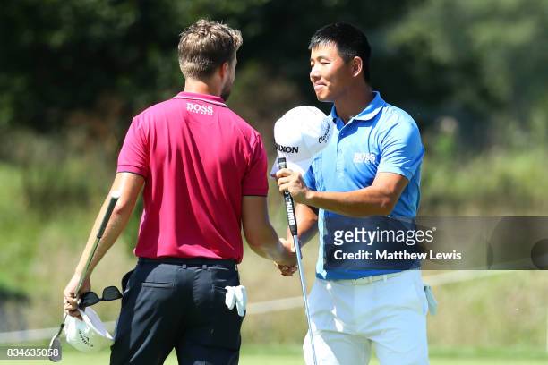Ashun Wu of China is congratulated on his victory by Rikard Karlberg of Sweden on the 17th green during the 32 qualifiers matches of the Saltire...