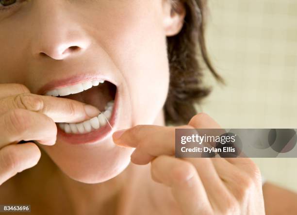 a woman in her 40s flossing her teeth. - zahnseide stock-fotos und bilder