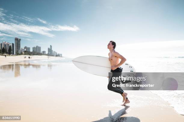 surfer running on surfers paradise beach in australia - surfers paradise stock pictures, royalty-free photos & images