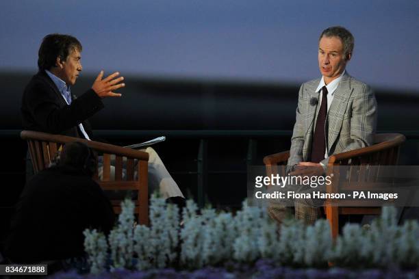 Former Tennis player John McEnroe chats with BBC presenter John Inverdale under studio lighting outside as dusk falls at Wimbledon