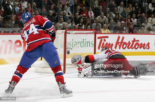 Guillaume Latendresse of the Montreal Canadiens takes a shot that passes through the crease as Cam Ward of the Carolina Hurricanes tries to make a...