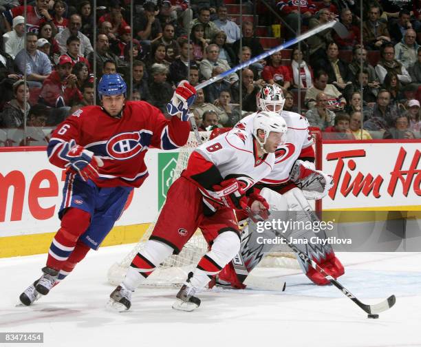 Tom Kostopoulos of the Montreal Canadiens skates after Matt Cullen the Carolina Hurricanes as he carries the puck and team mate Cam Ward of the...