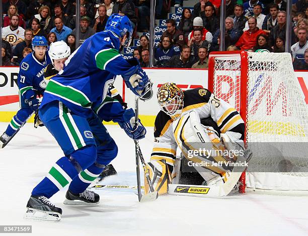 Tim Thomas of the Boston Bruins makes the save on Daniel Sedin of the Vancouver Canucks with teammate Jason Krog looking on during their game at...