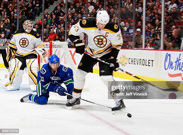Tim Thomas of the Boston Bruins watches as teammate Zdeno Chara is checked by Daniel Sedin of the Vancouver Canucks during their game at General...