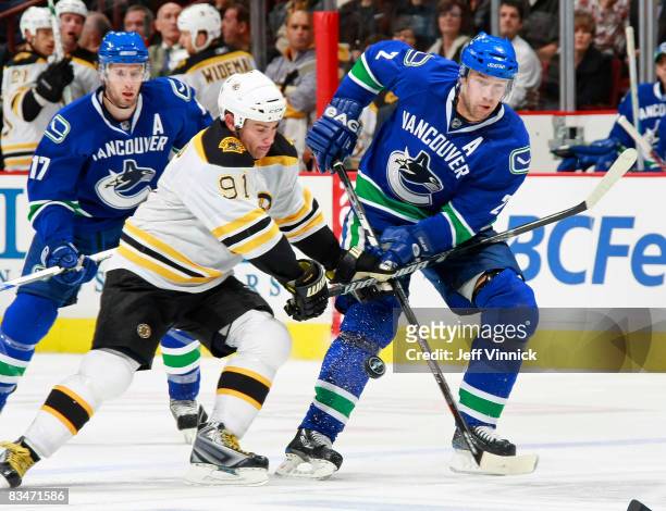 Ryan Kesler of the Vancouver Canucks watches as teammate Mattias Ohlund checks Marc Savard of the Boston Bruins during their game at General Motors...