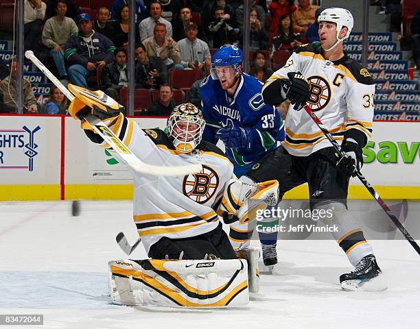 Tim Thomas of the Boston Bruins makes a save while teammate Zdeno Chara checks Henrik Sedin of the Vancouver Canucks during their game at General...